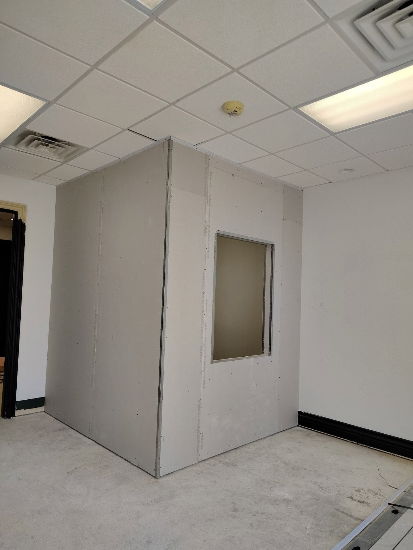 Audibel Gretna during renovation — hung drywall, metal corner beads, and bare concrete floor