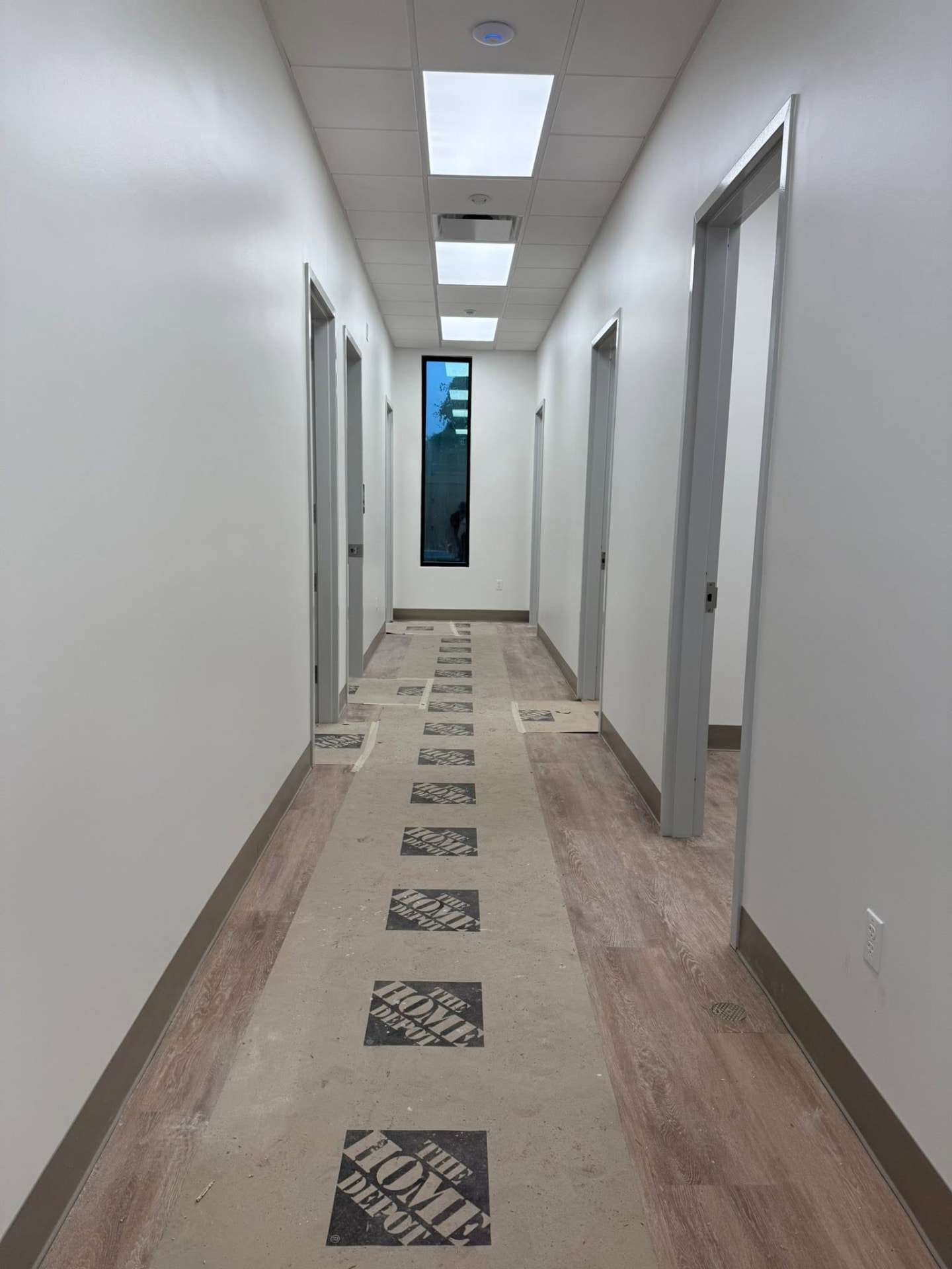 Completed urology clinic corridor with painted walls, new flooring, door frames, and ceiling panels