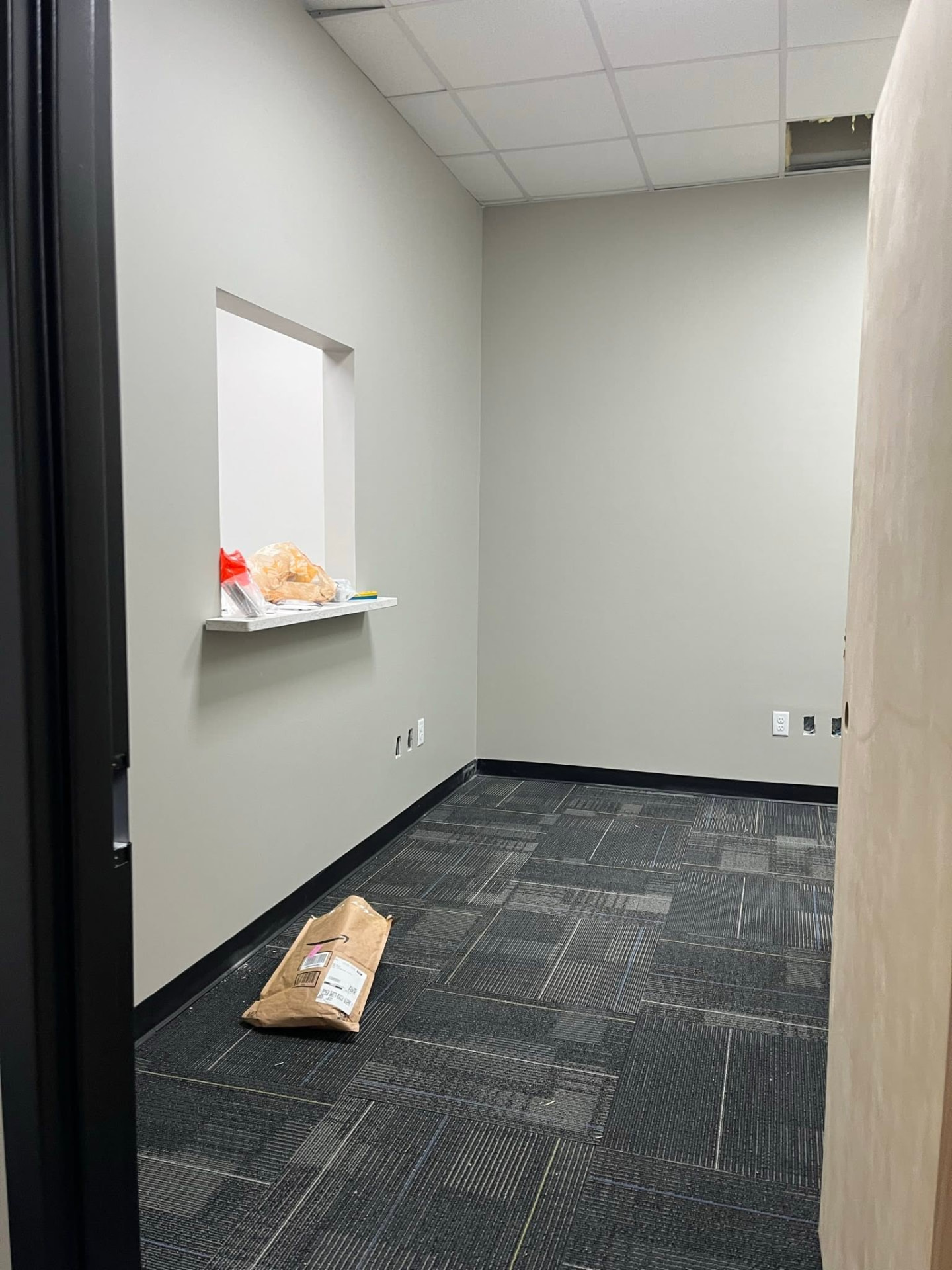 Completed Audibel Houma office with painted walls, carpet tile, black cove base, and pass-through ledge