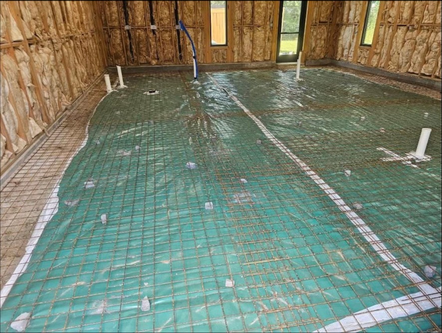 Vapor barrier, reinforcing steel, and under-slab plumbing set before the pour